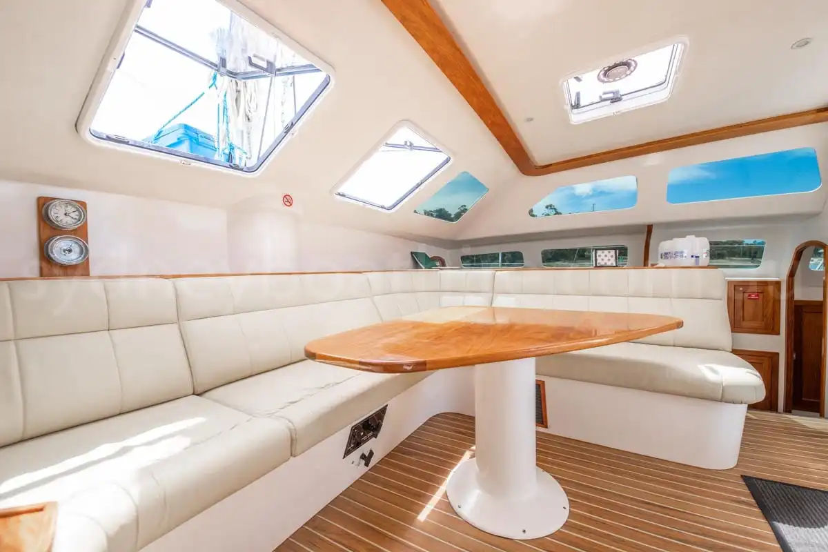 Panoramic saloon lounge and dining table inside the Wanderlust motoryacht by Dreamboats with wraparound windows.