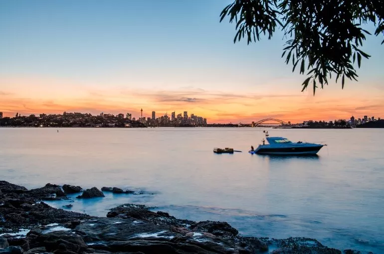 Inception sports cruiser anchored near a city skyline at sunset.