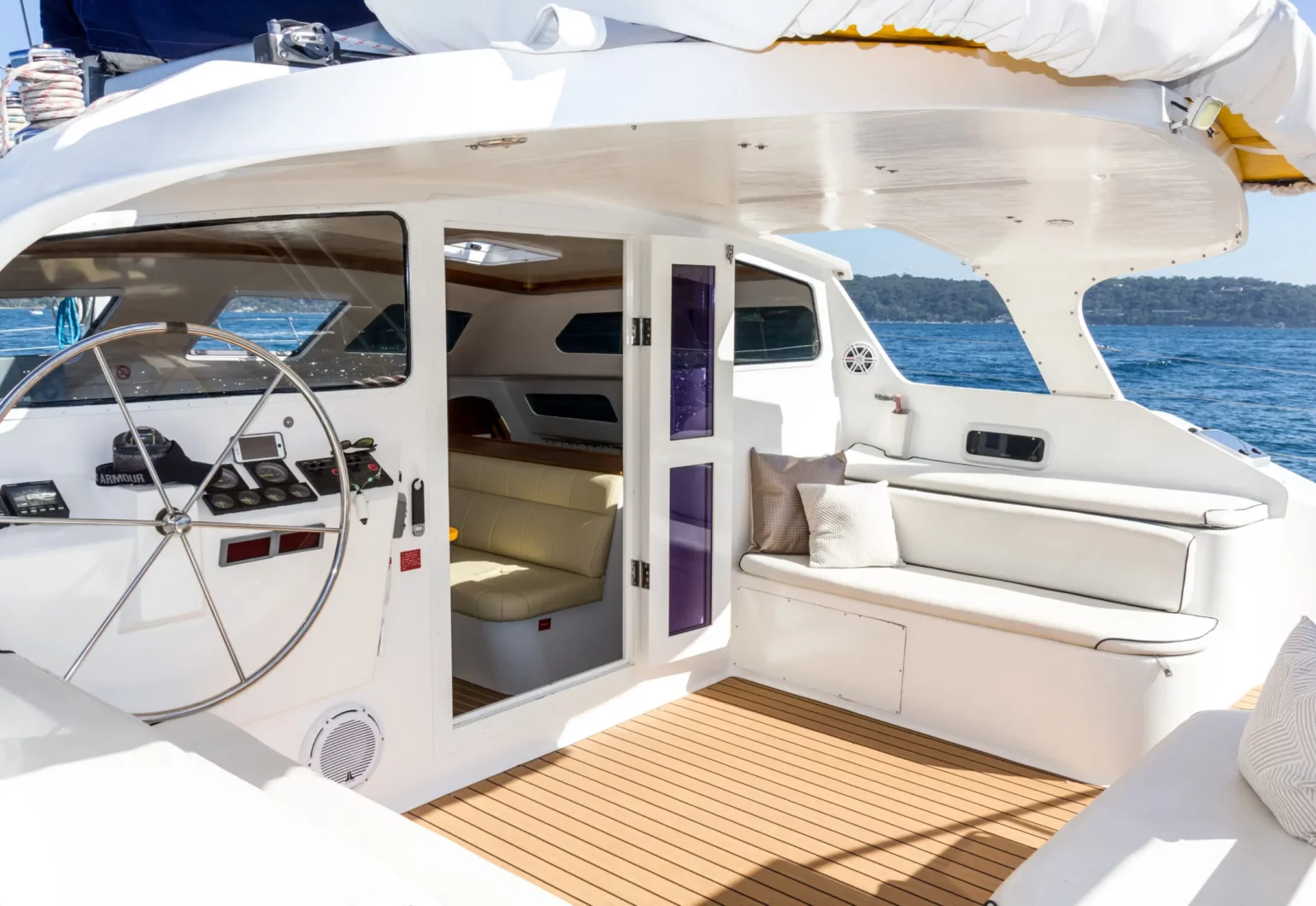 Bright interior of a boat with a steering wheel and seating area. wanderlust boat sydney