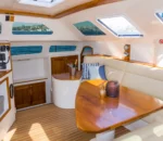 Interior saloon and dining lounge of the Wanderlust motoryacht by Dreamboats with panoramic windows and teak finish.