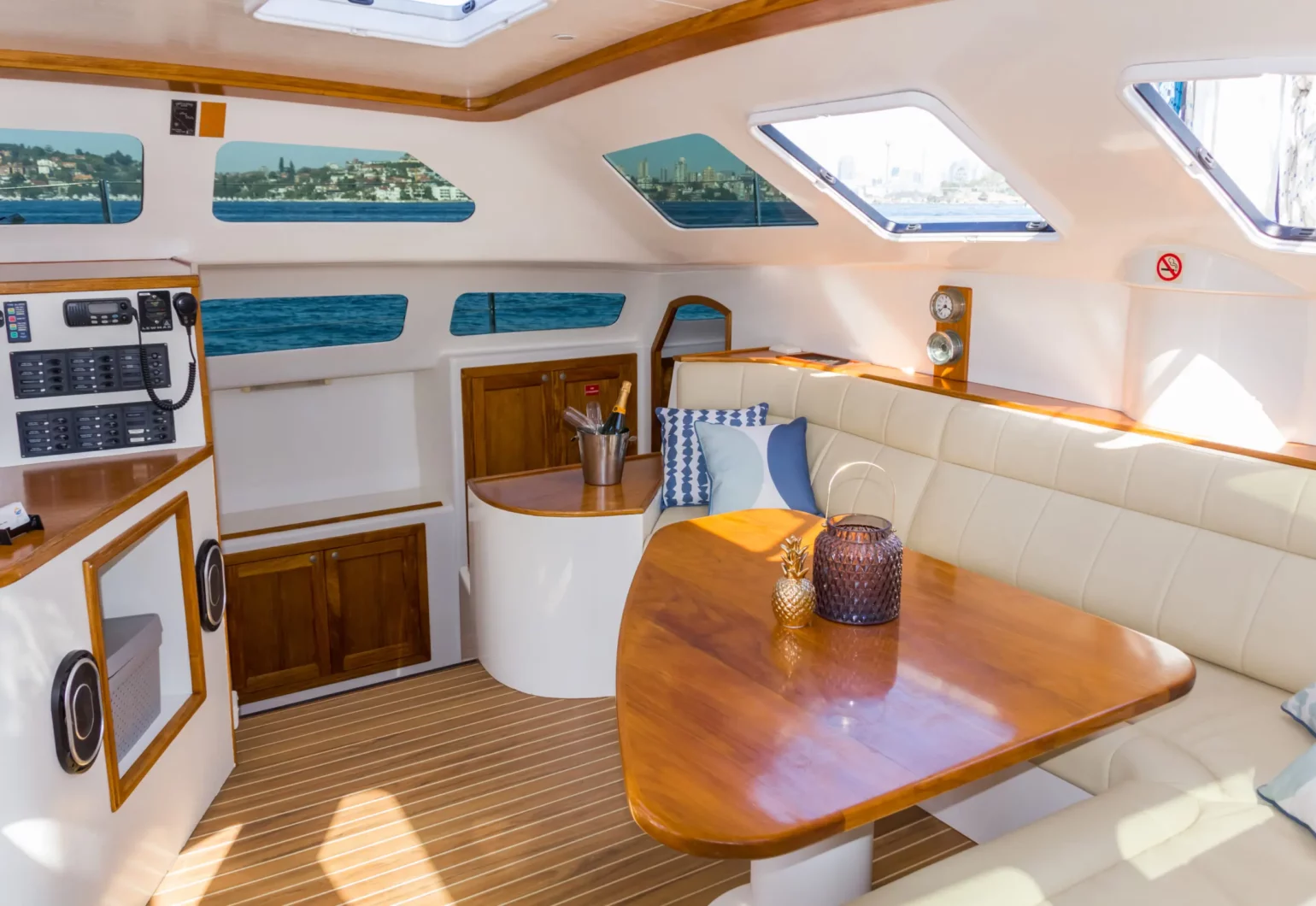 Interior saloon and dining lounge of the Wanderlust motoryacht by Dreamboats with panoramic windows and teak finish.