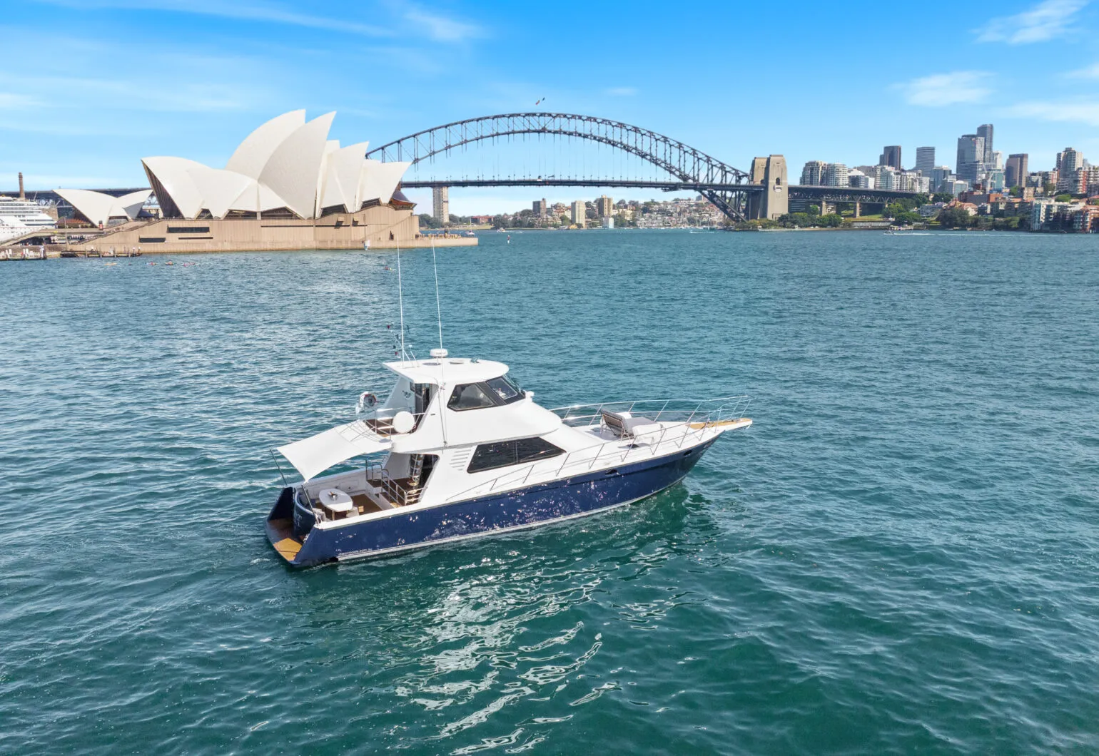 State of the Art yacht cruising in Sydney Harbour with the Opera House and Harbour Bridge in the background