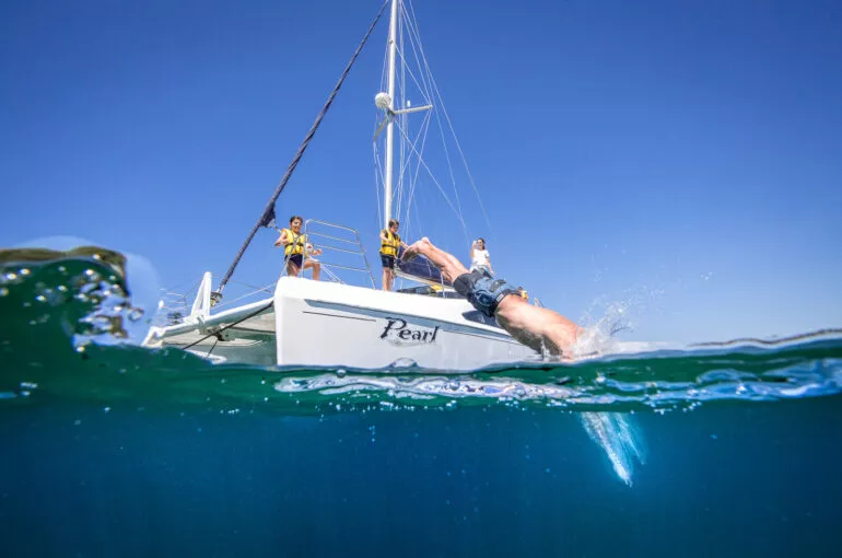 Sailors on a Pearl Catamaran enjoy a sunny day on the water.