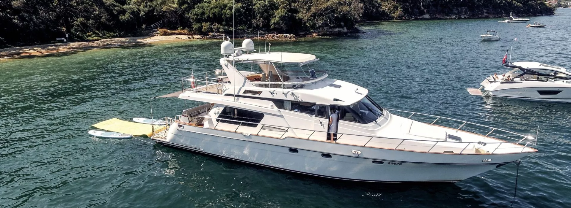 Enigma boat anchored in Sydney's tranquil waters surrounded by greenery.