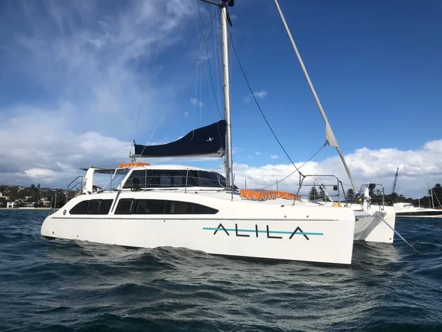 Sailing vessel named Alila anchored in calm waters under a blue sky.