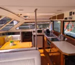 Spacious interior of the Spellbound boat featuring a dining area and kitchen.