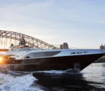 Ghost II Superyacht cruising near a bridge at sunset.