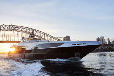 ghost 1 Ghost II Superyacht cruising near a bridge at sunset.