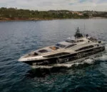 Sleek Ghost II Superyacht cruising on calm waters with scenic background. Variation #1: Ghost II Superyacht navigating through serene waters with lush hills nearby.