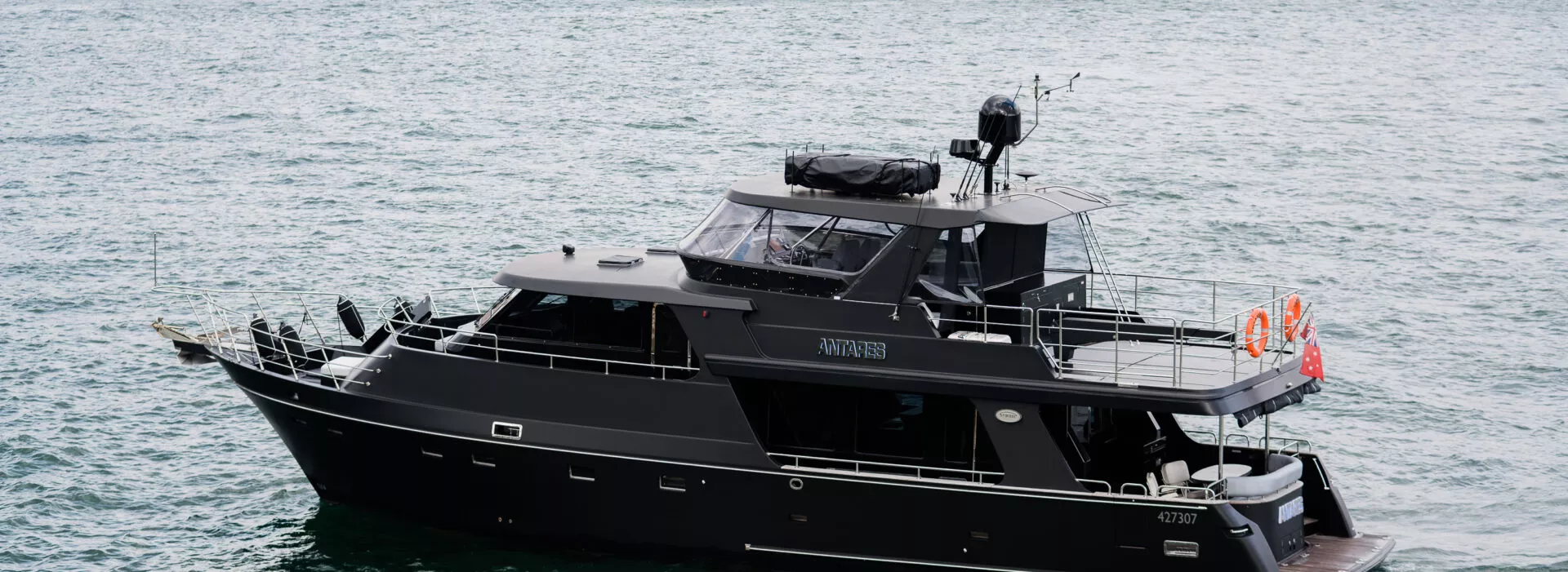 Antares boat in Sydney anchored on calm waters. Antares boat docked in Sydney with a sleek black design.