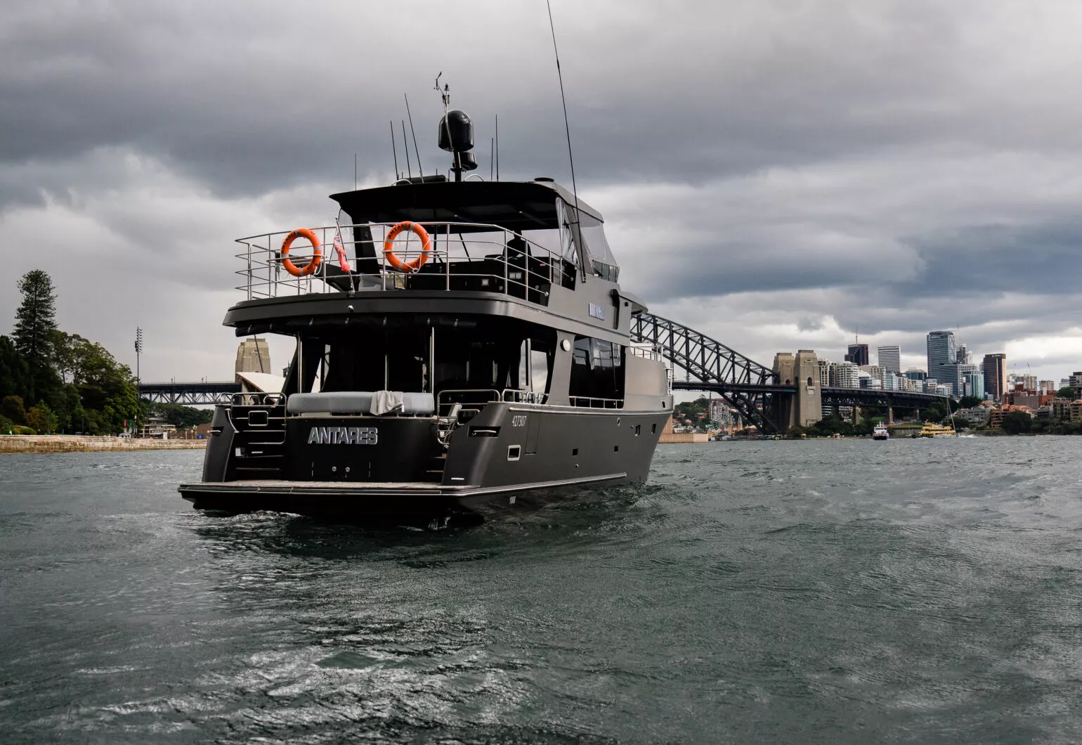 Antares boat in Sydney navigating through cloudy waters with city skyline.