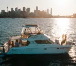 Life’s Good catamaran sailing near a city skyline at sunset. Variation #1: Life’s Good catamaran anchored with city skyline glowing in the background.