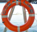 Bright orange lifebuoy labeled "OCEAN LIFE" against a water background.