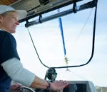 Sailing on a catamaran, a person steers while enjoying ocean life in Sydney.