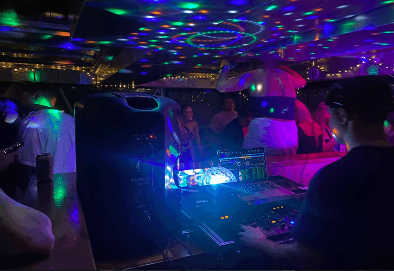 Colorful lights illuminate a lively party on a catamaran in Sydney.