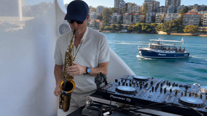 saxophonist-musician-addon-yachtcharter Live saxophonist and drummer performing outdoors on a Sydney Harbour yacht